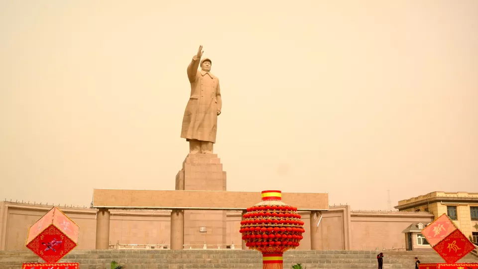 mao statue in background. red lanterns in foreground. 