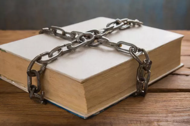 Ai generated photo realistic image of book with chains wrapped around it.