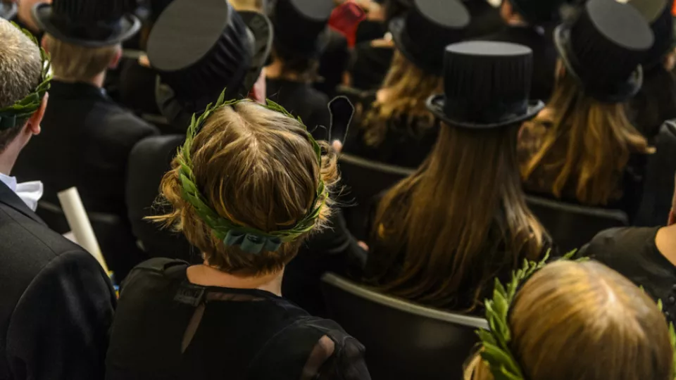 heads from behind, some in doctoral hats, some with laurel-wreaths