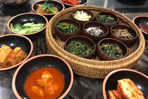 Table with korean food in various small bowls. Photo.