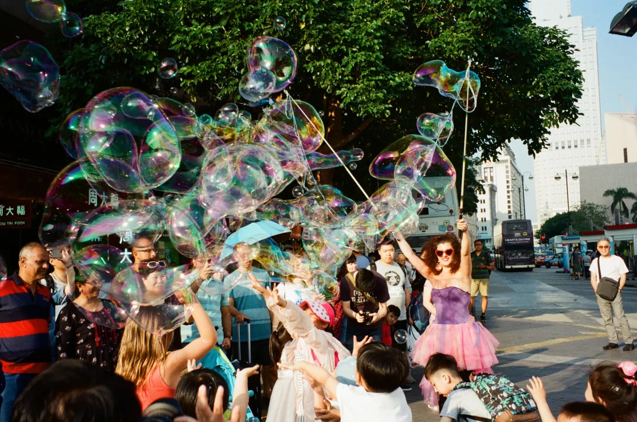 Woman making large soap bubbles in a crowd. Hong Kong. Photo