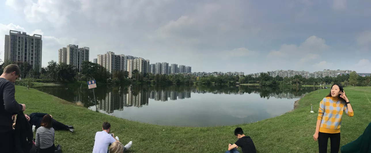 Students sitting relaxing in park with lake in background. Chengdu, China.Photo